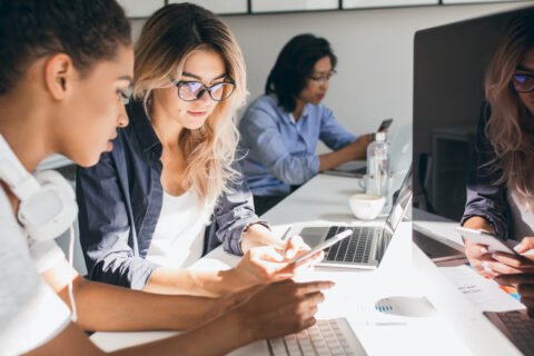 pretty-freelance-copywriter-texting-message-phone-while-her-colleagues-typing-keyboards-indoor-portrait-young-programmers-different-ethnicities-working-office